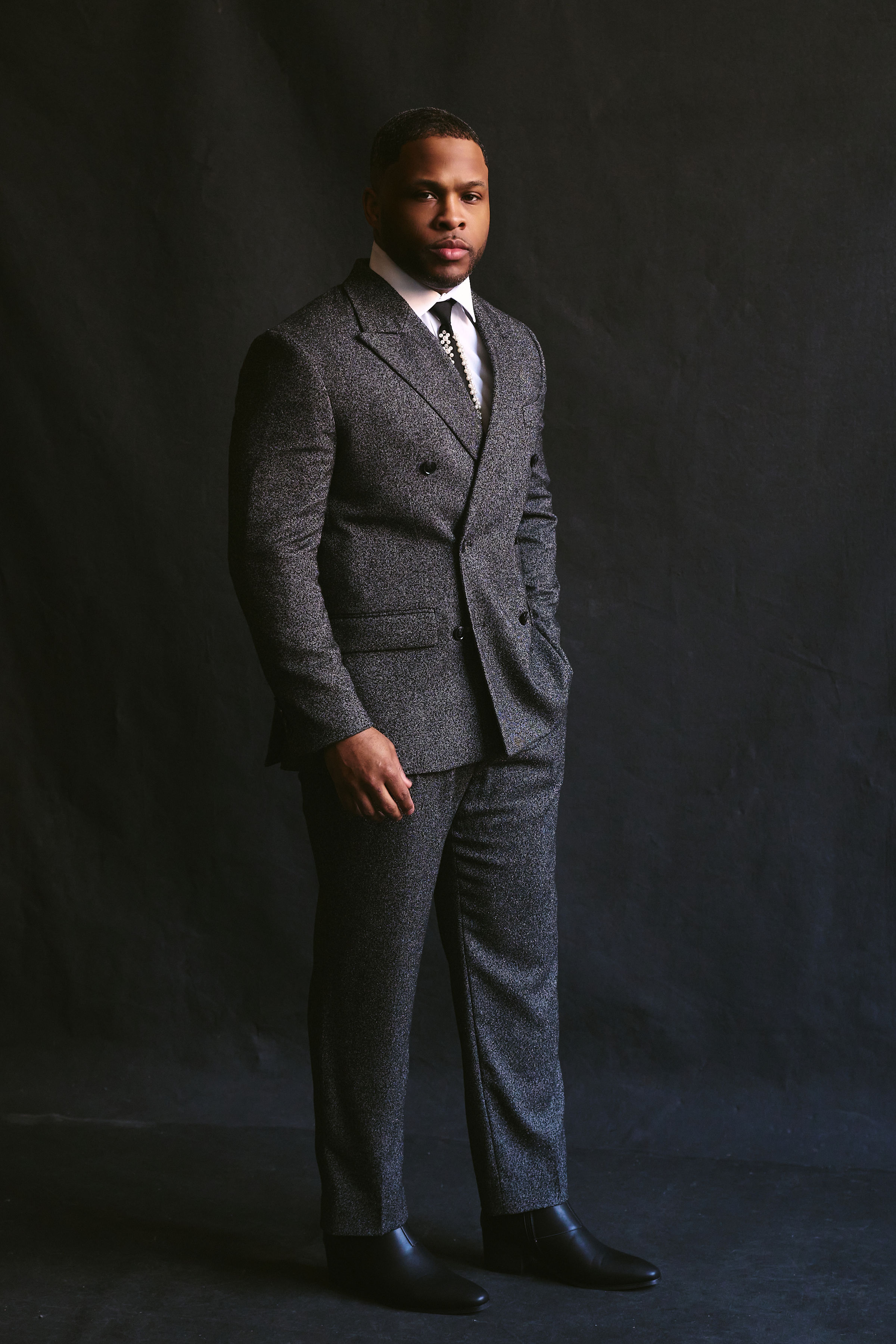 Studio portrait of Dion Dawson in a tailored tweed suit