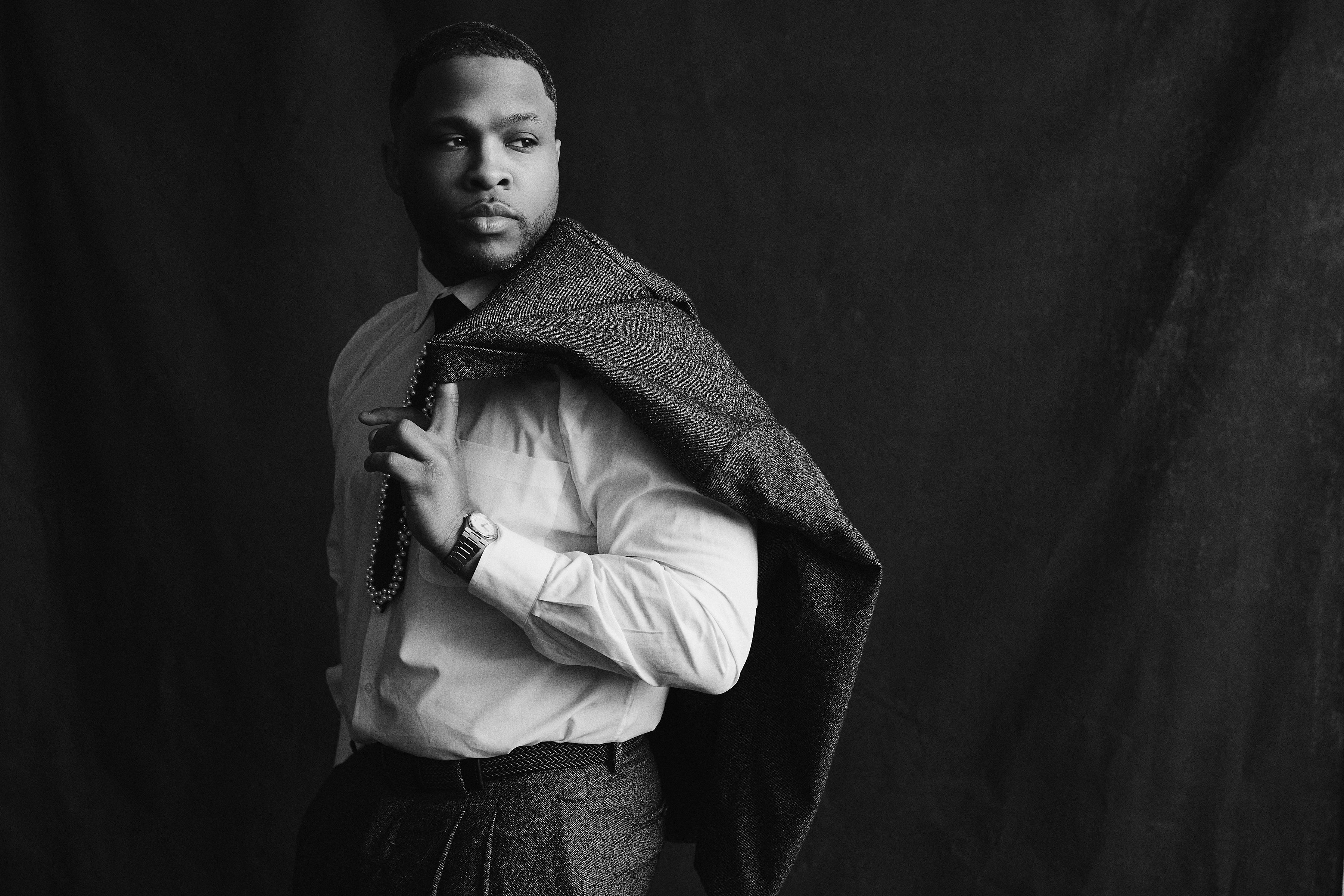 Studio portrait of Dion Dawson with his jacket over one shoulder