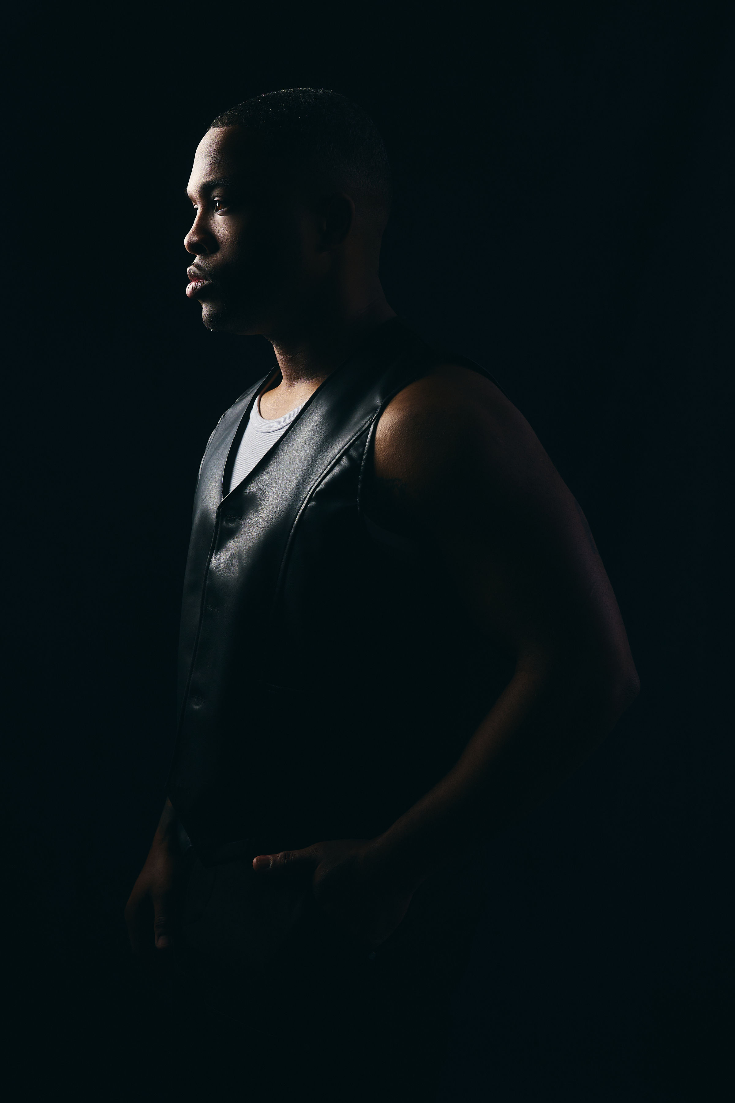 Low-key studio profile portrait of Dion Dawson in shadow