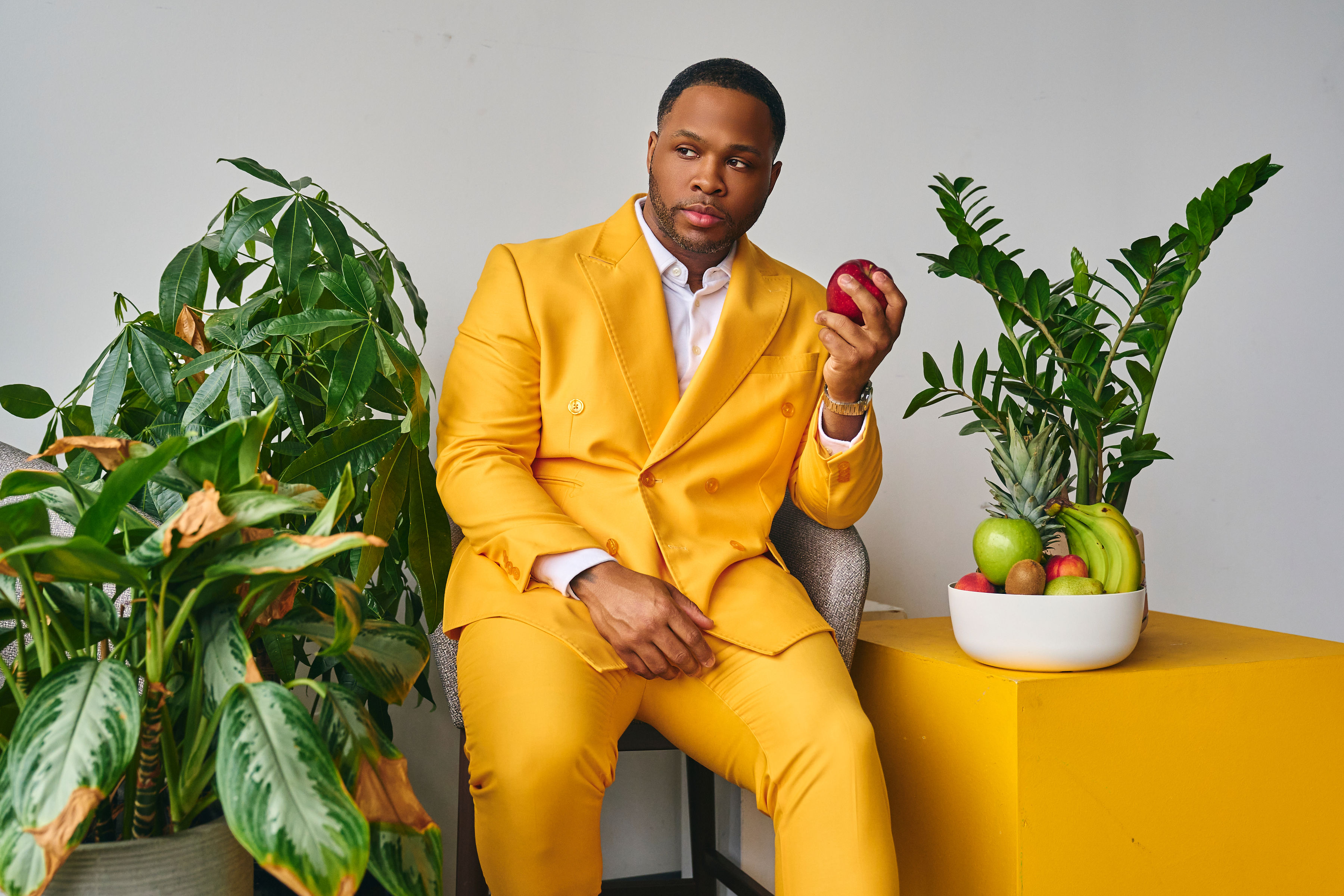 Dion Dawson in a yellow suit surrounded by plants and fresh fruit